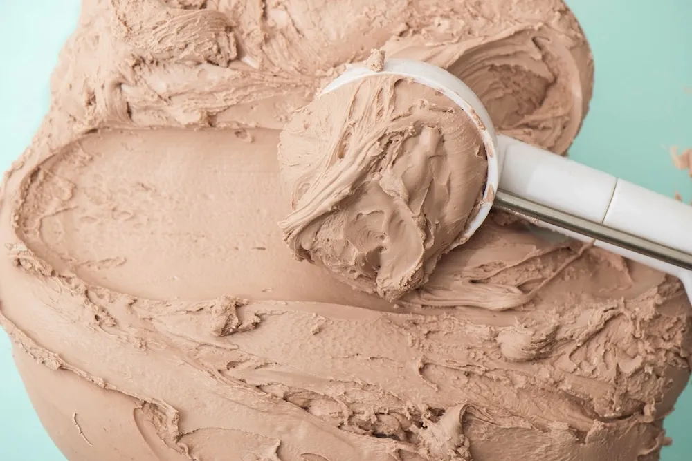 Close-up of a scoop of light brown, clay-coloured ice cream in a tub, used to visually represent the appearance of pale or clay-coloured stool